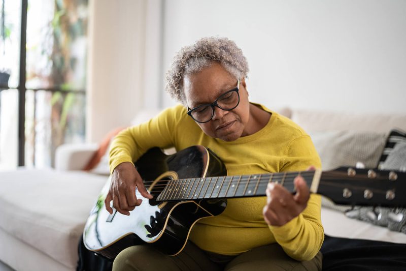 A woman practices the guitar.