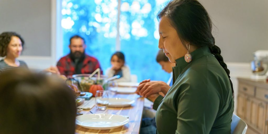 A woman prays before a meal.